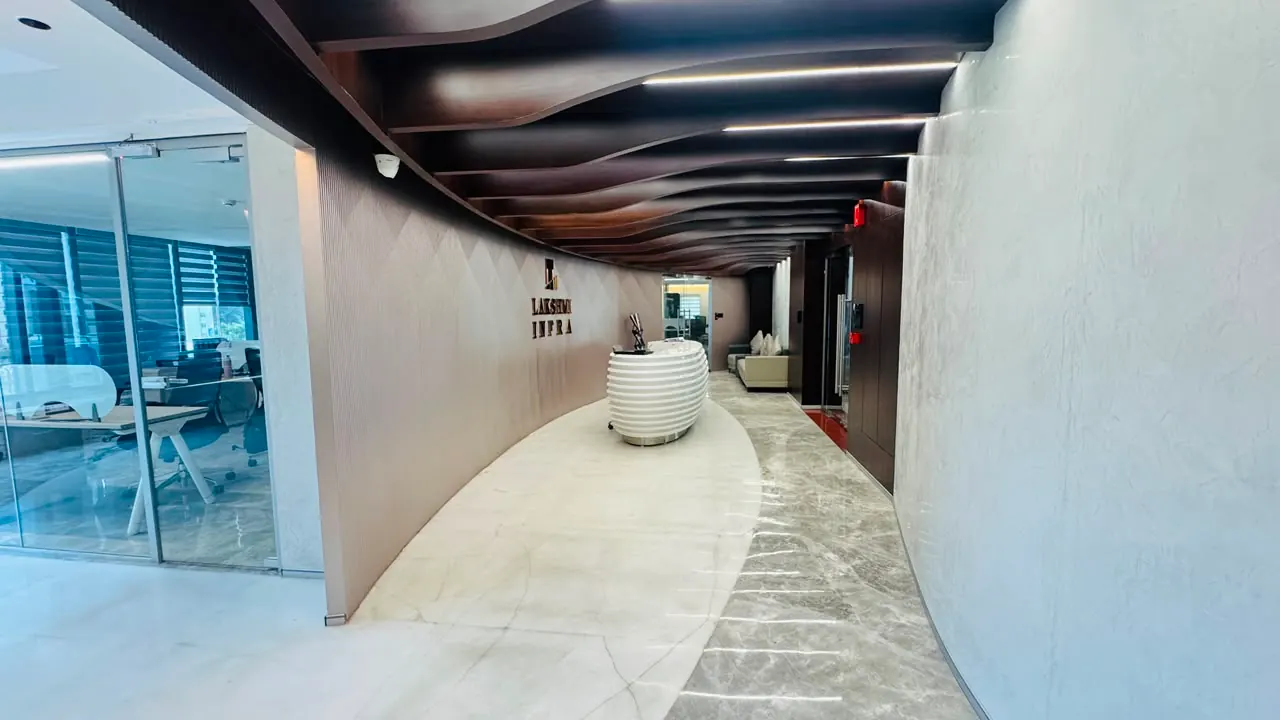 The curved approach to a corporate reception, marble floor and a wave-form timber ceiling running the length of the corridor